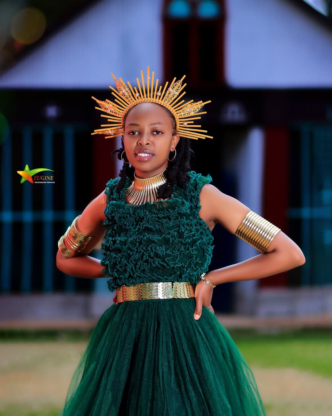 Birthday portrait of a young woman in a green ruffled dress and gold crown, hands on hips