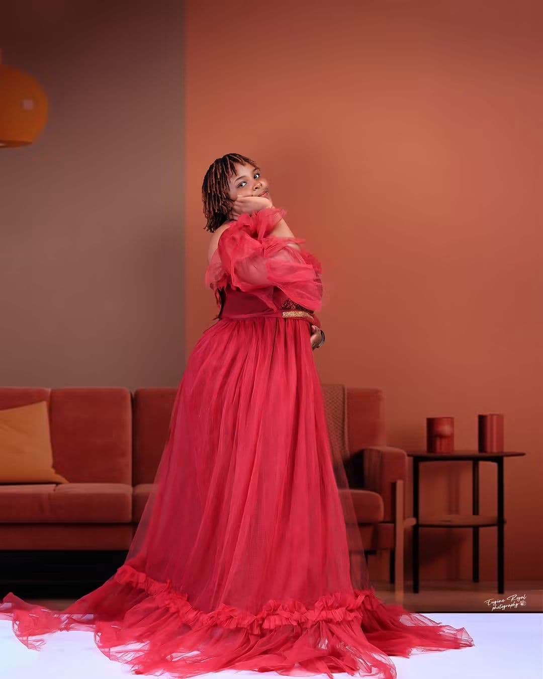 Woman in a flowing red tulle gown posing in a terracotta living-room studio set