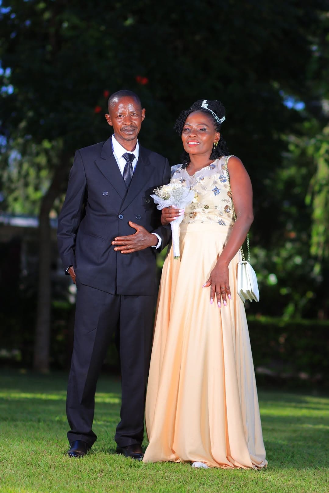Bride and groom standing arm in arm on the lawn, the bride holding her bouquet