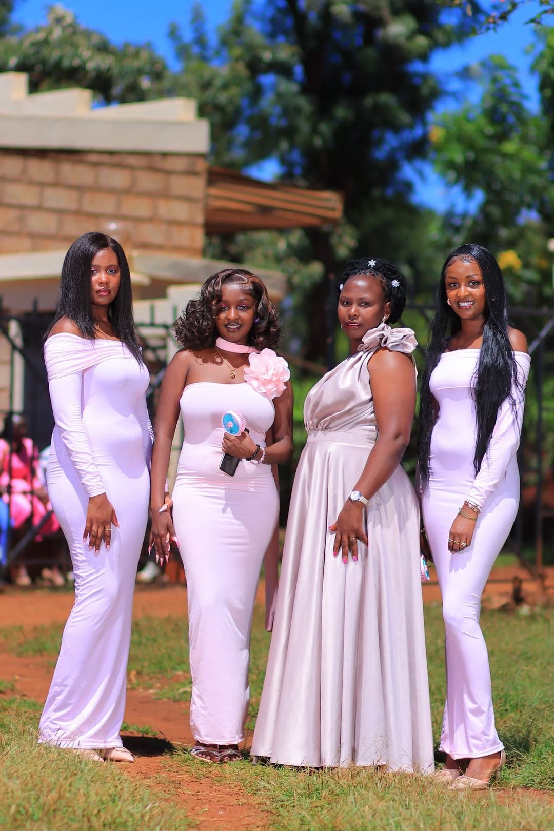 Four bridesmaids in blush gowns on a garden path