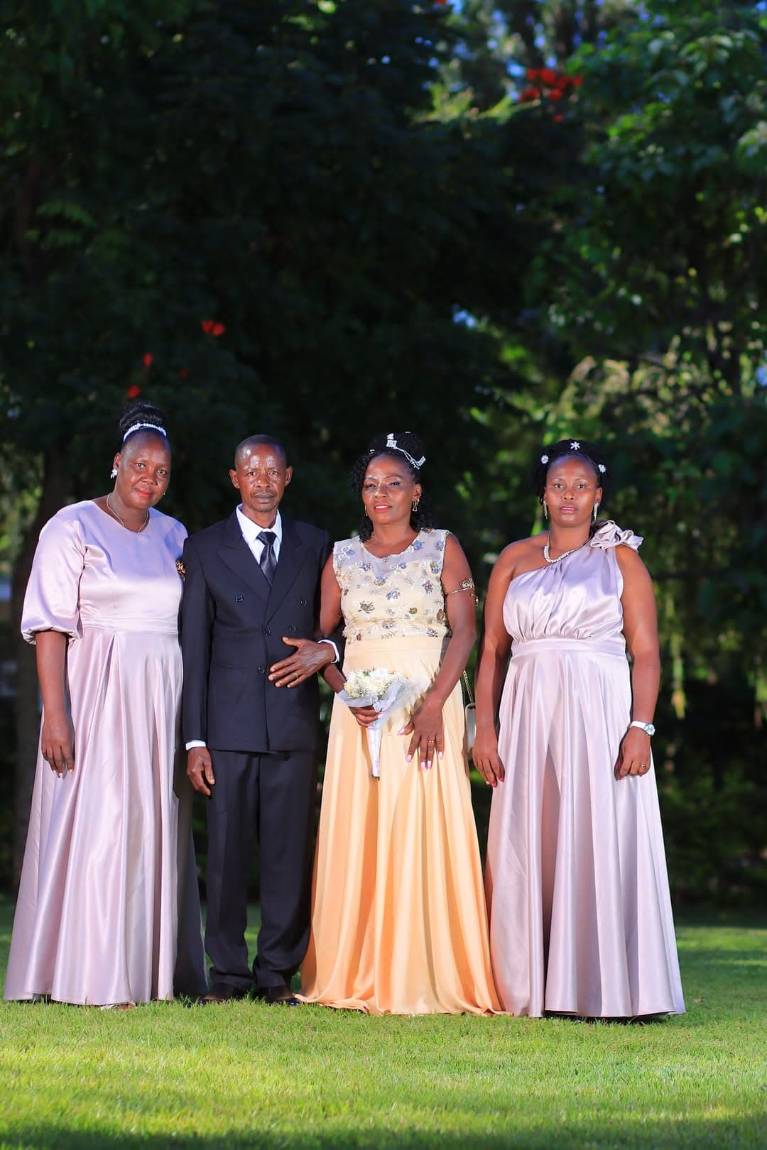 Bride and groom with two guests in blush gowns in the garden
