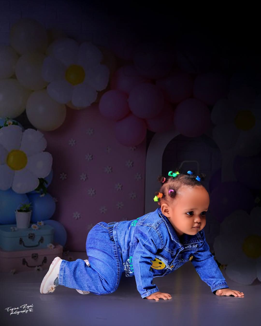 Baby in denim crawling across a floral balloon studio set