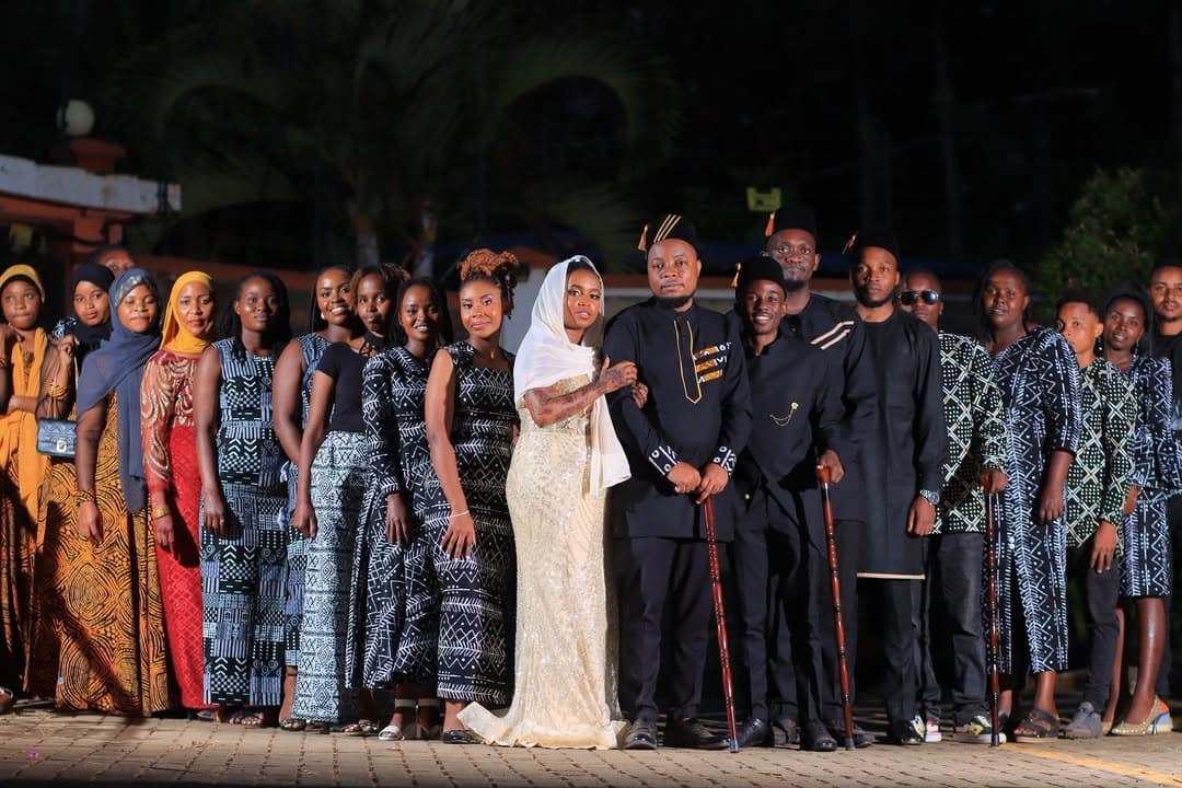 Large group in coordinated African-print outfits posing at night