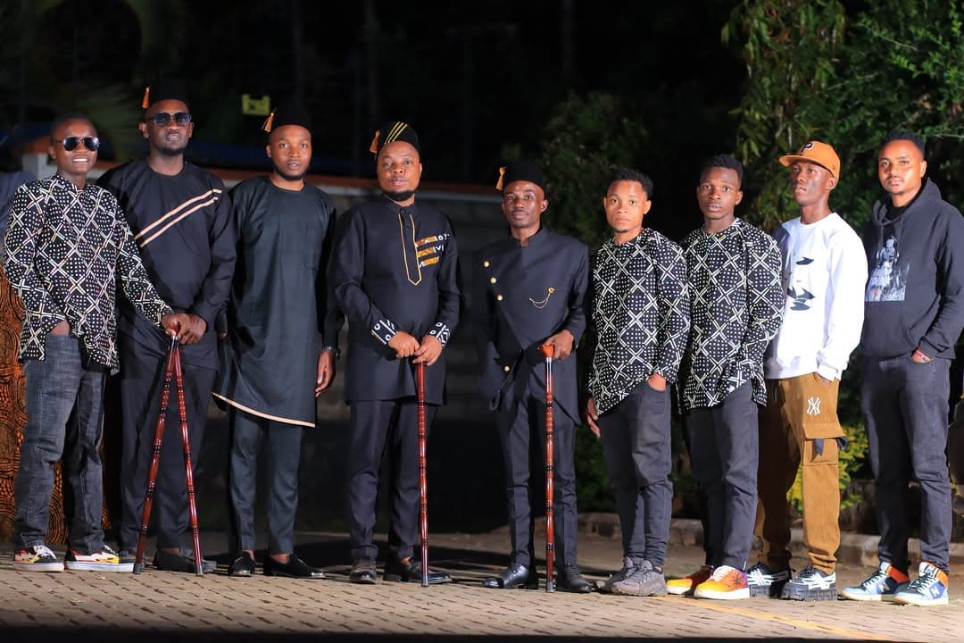 Line of men in coordinated black and patterned outfits at night