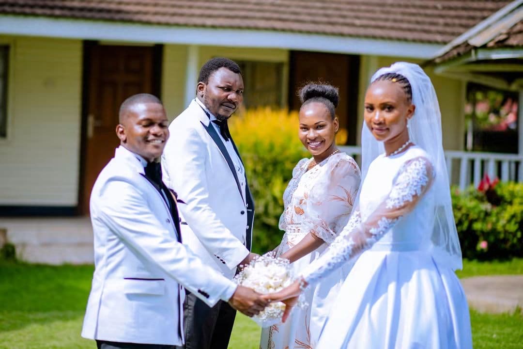 Bride and groom holding the bouquet together with their best man and maid of honour