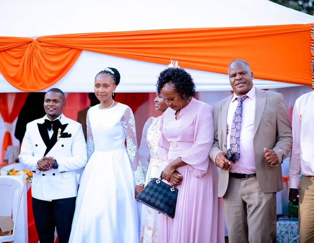Bride and groom arriving with family under an orange-and-white reception tent