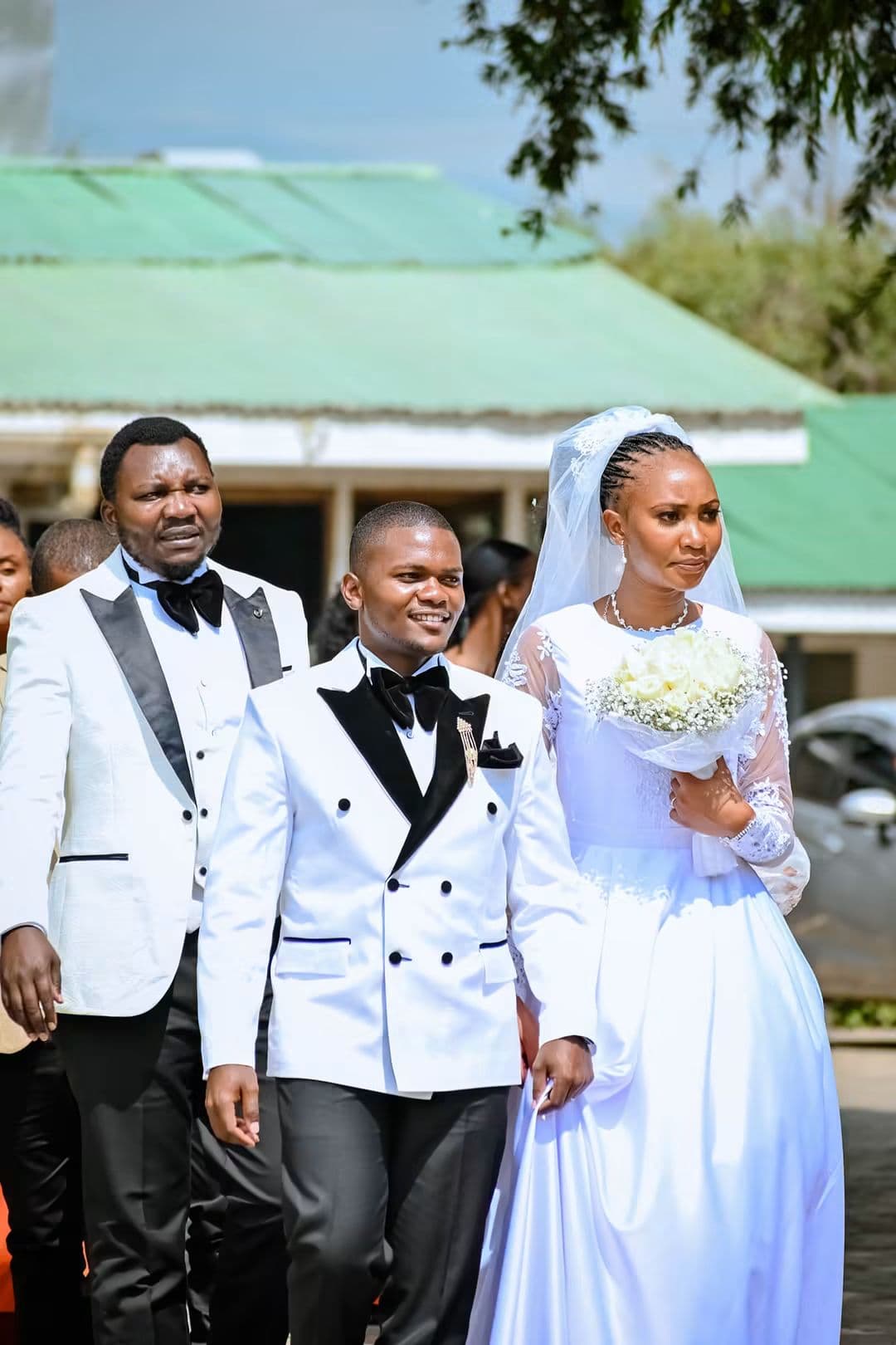 Bride and groom walking out together with the best man
