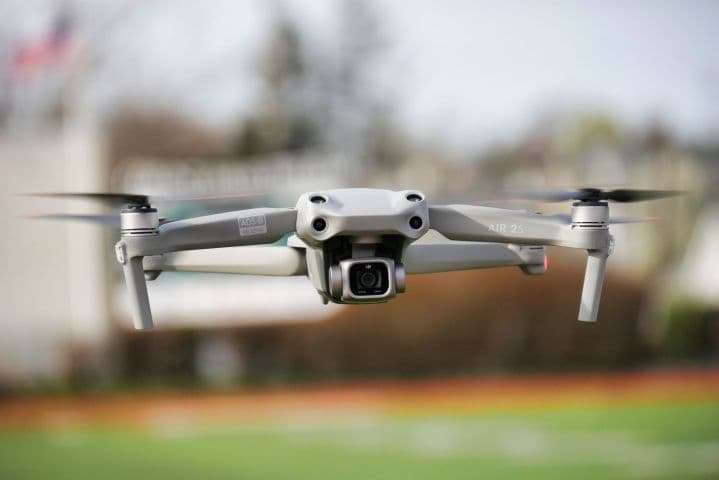 Camera drone hovering in front of a white building