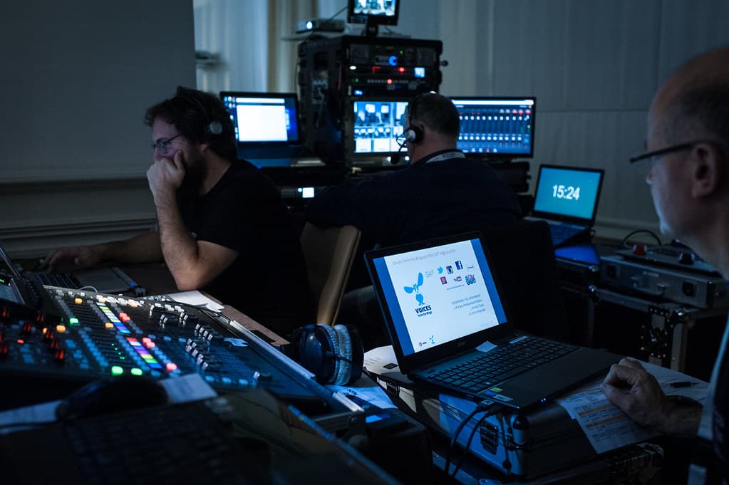Production crew running a live stream from a desk of monitors and mixing gear