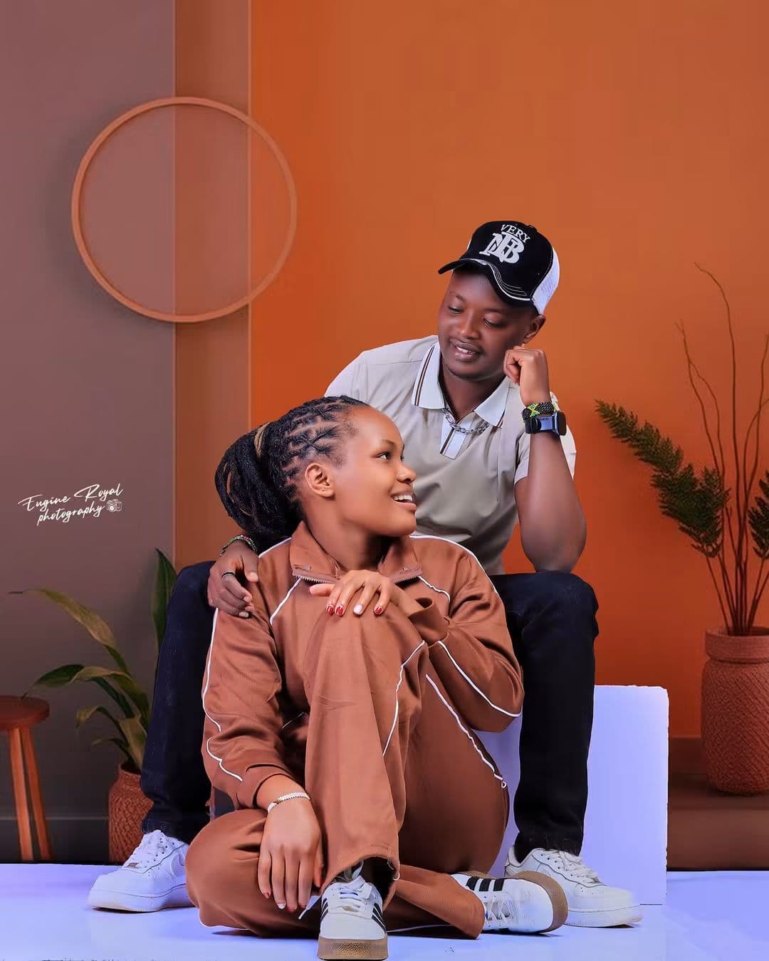 Couple in brown and beige outfits posing together on an orange studio set