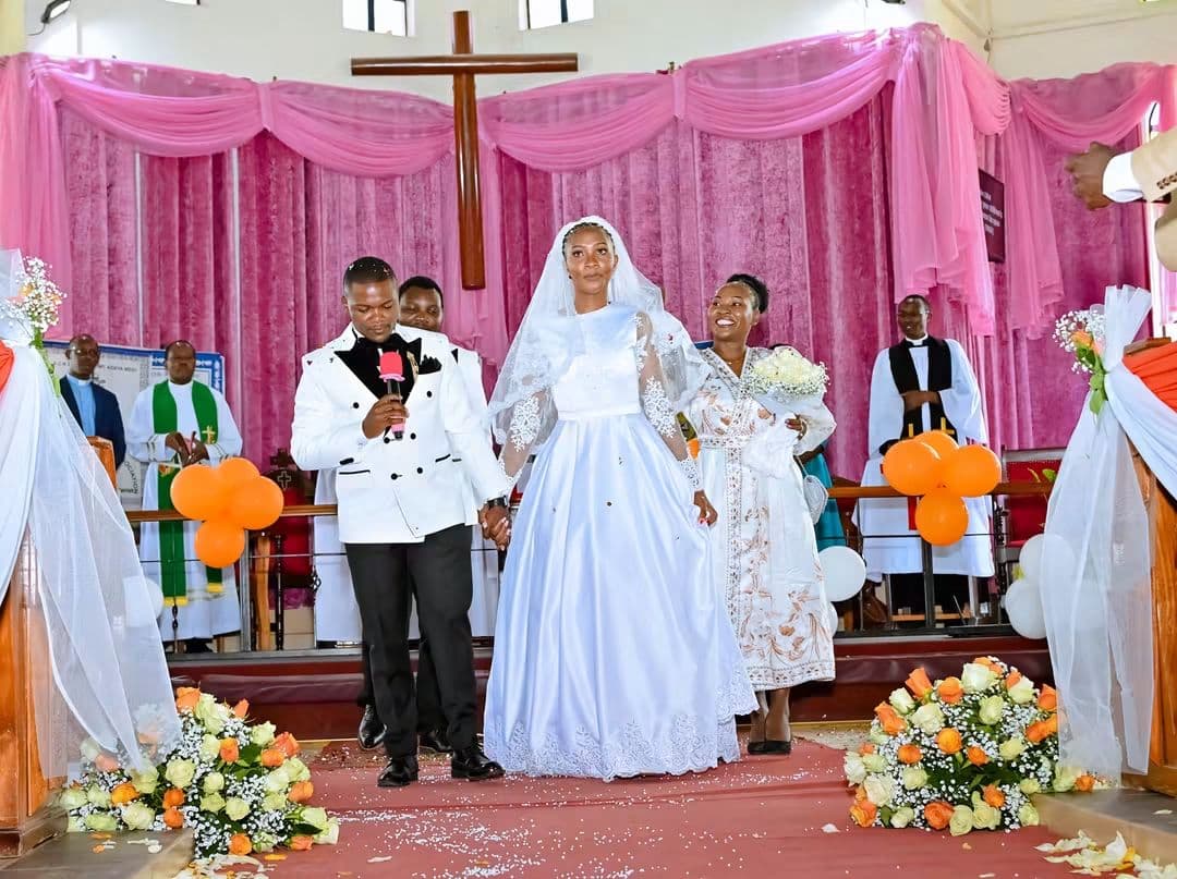 Bride and groom at the altar of a church decorated in pink and white